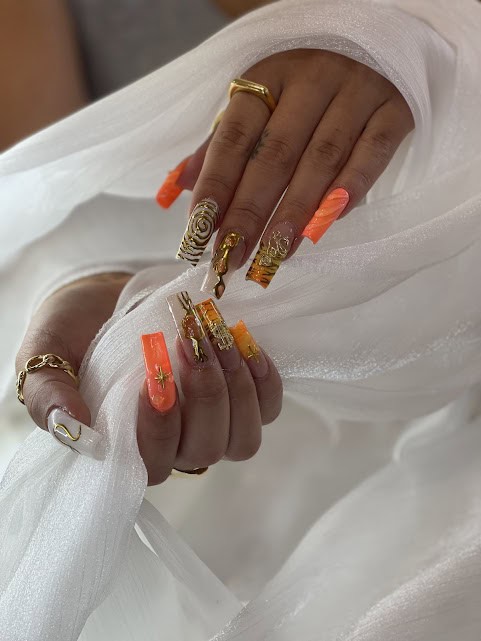 Beautiful orange and gold nail design with intricate details and embellishments. Perfect for special.